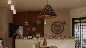 Ein modernes Interieur mit einem zentralen Holztisch, hängenden Pendelleuchten und einer Küchenzeile im Hintergrund.