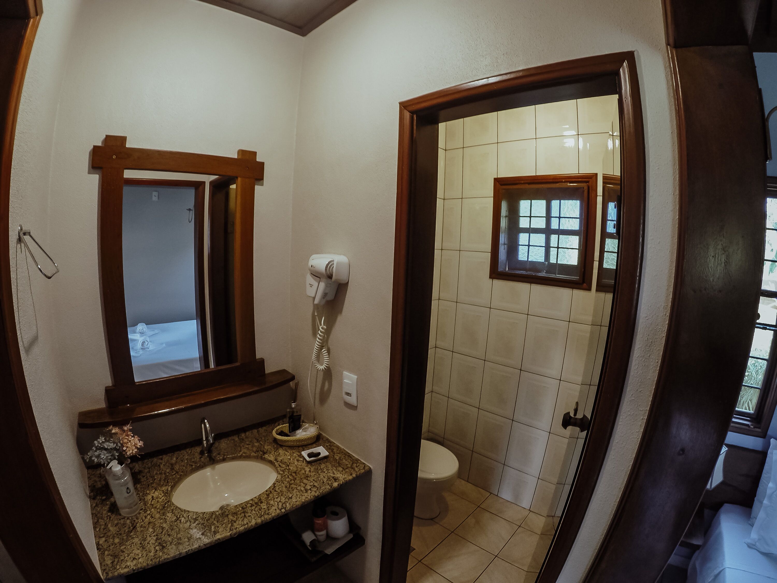 Un baño con lavabo, espejo, secador de pelo e inodoro.