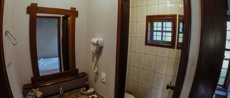 A bathroom with a sink, mirror, hairdryer, and toilet.