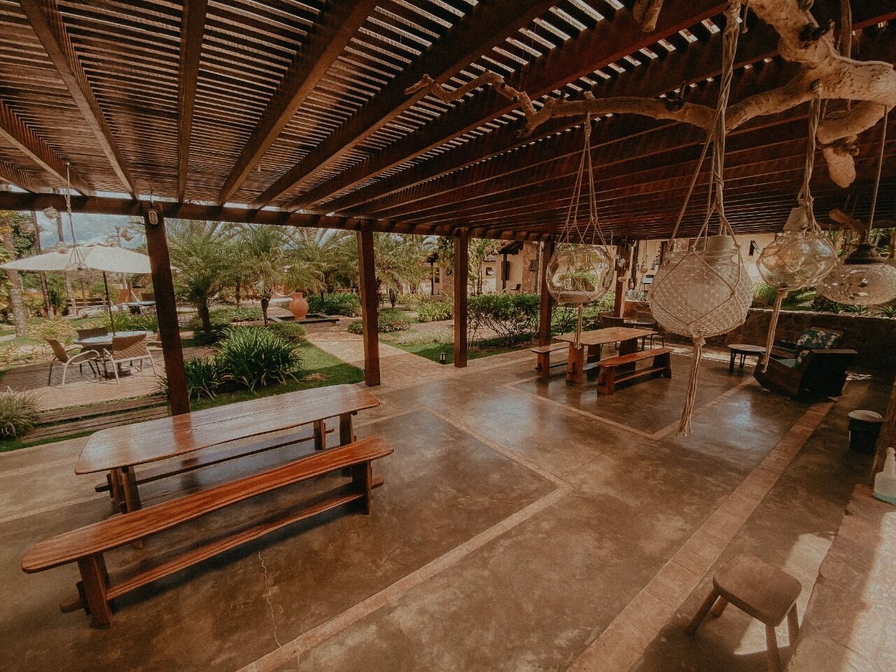 An outdoor patio area with wooden benches and hanging light fixtures.