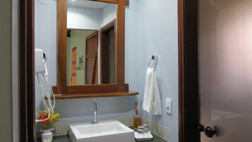 Uma casa de banho com uma pia branca, um espelho, um porta-toalhas e uma porta.