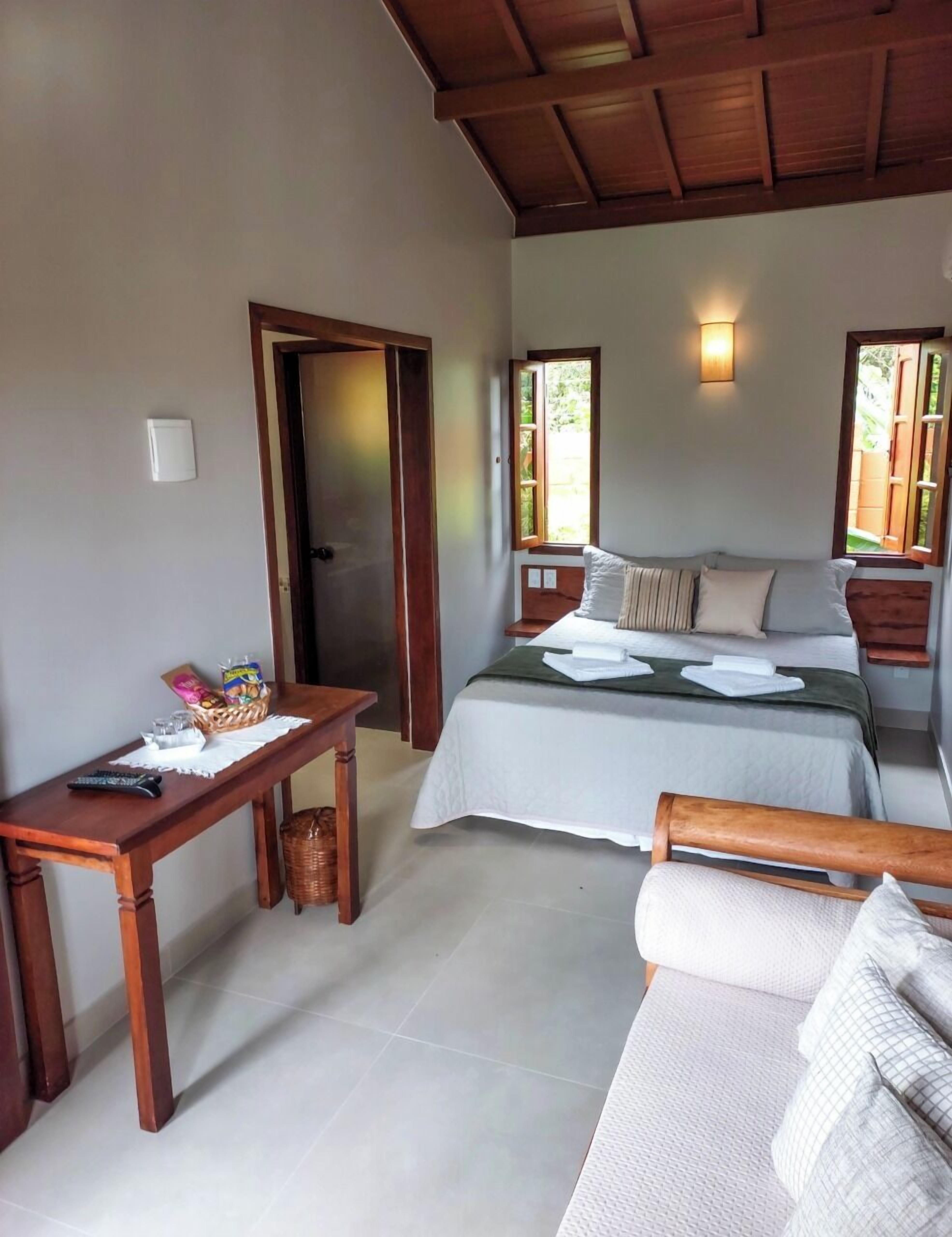 A bedroom with a bed, bedside tables, a desk, and a window.