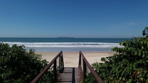 Una escalera de madera que lleva a una playa con vista despejada al océano.