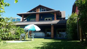 A two-story house with a tiled roof, a balcony, and a covered patio area.