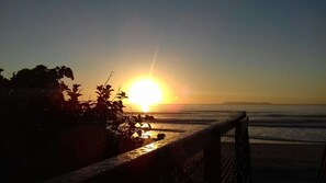 Atardecer sobre el océano con una playa y una cerca en primer plano.