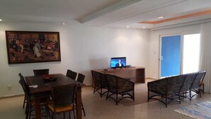 A dining area with a wooden table and chairs, a television, and a painting on the wall.