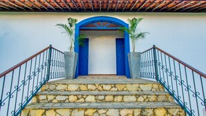 Una escalera de piedra que conduce a una puerta azul con tejado de baldosas arriba.