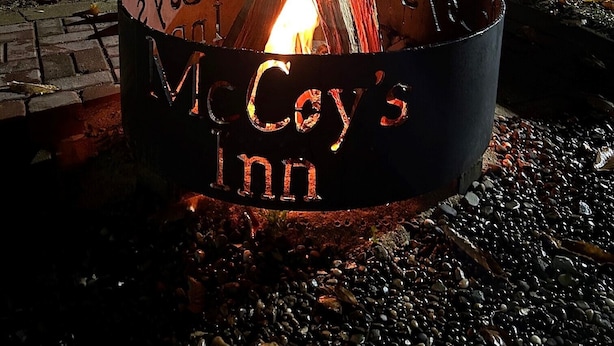 A metal fire pit with the inscription "McCoy's Inn" and a lit fire. - McCoy's Inn (Ripley)