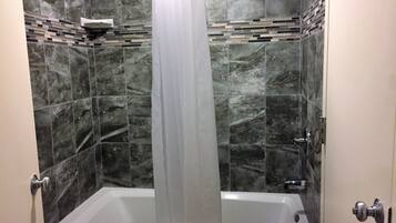 Un baño con bañera, cortina de ducha y pared de azulejos con diseño de mosaico.