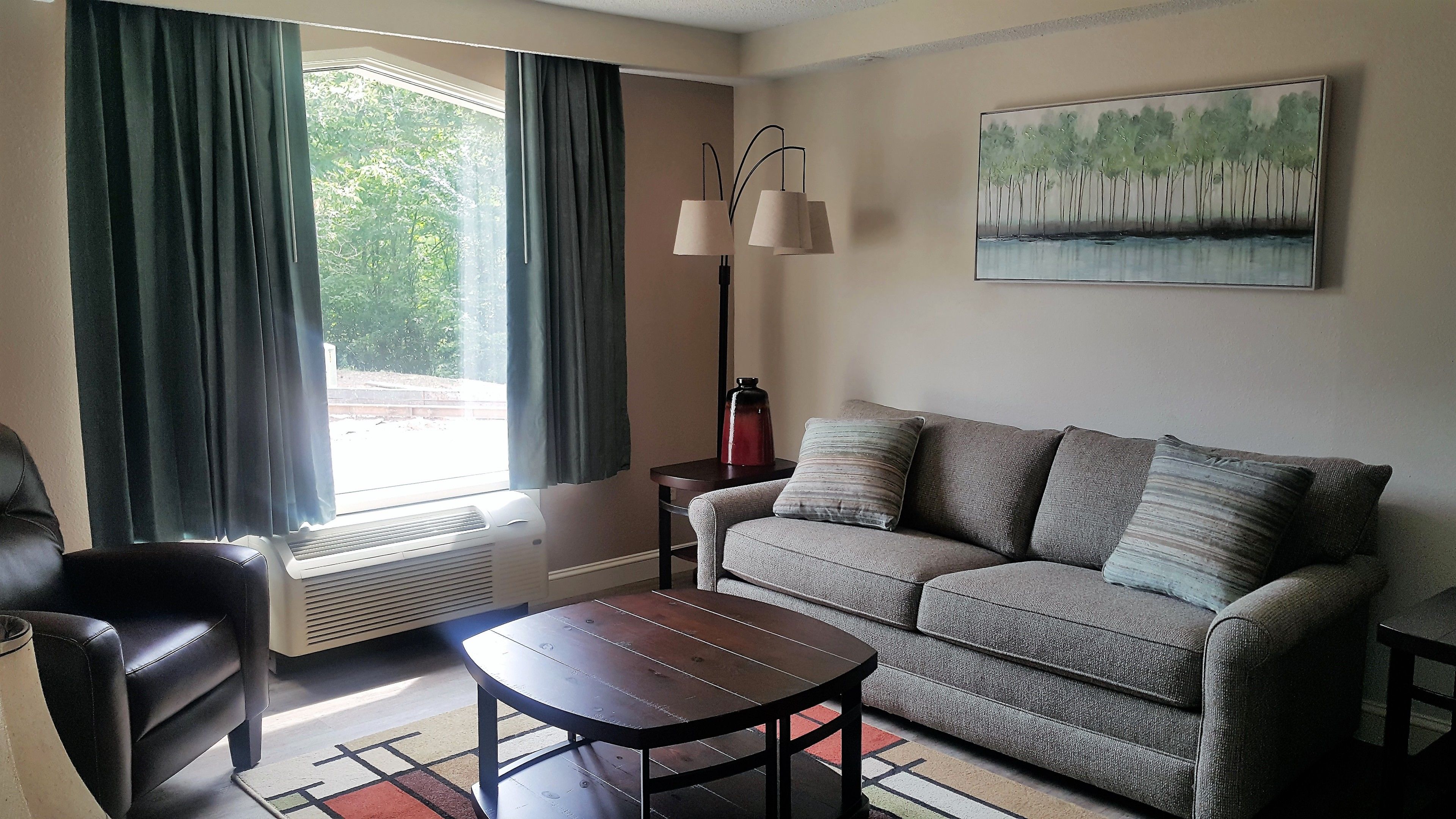A living room with a sofa, a coffee table, a lamp, and a painting on the wall.