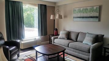 A living room with a sofa, a coffee table, a lamp, and a painting on the wall.