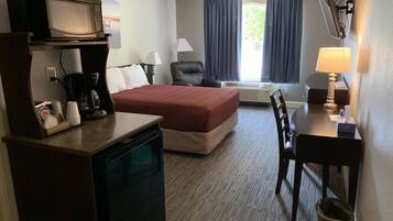 Une chambre d’hôtel équipée d’un lit, d’un bureau, d’une chaise, d’un four à micro-ondes, d’une machine à café et d’une télévision.
