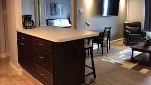 A modern kitchen with a central island, dark wooden cabinets, and a dining area with a table and chairs. - McCoy's Inn (Ripley)