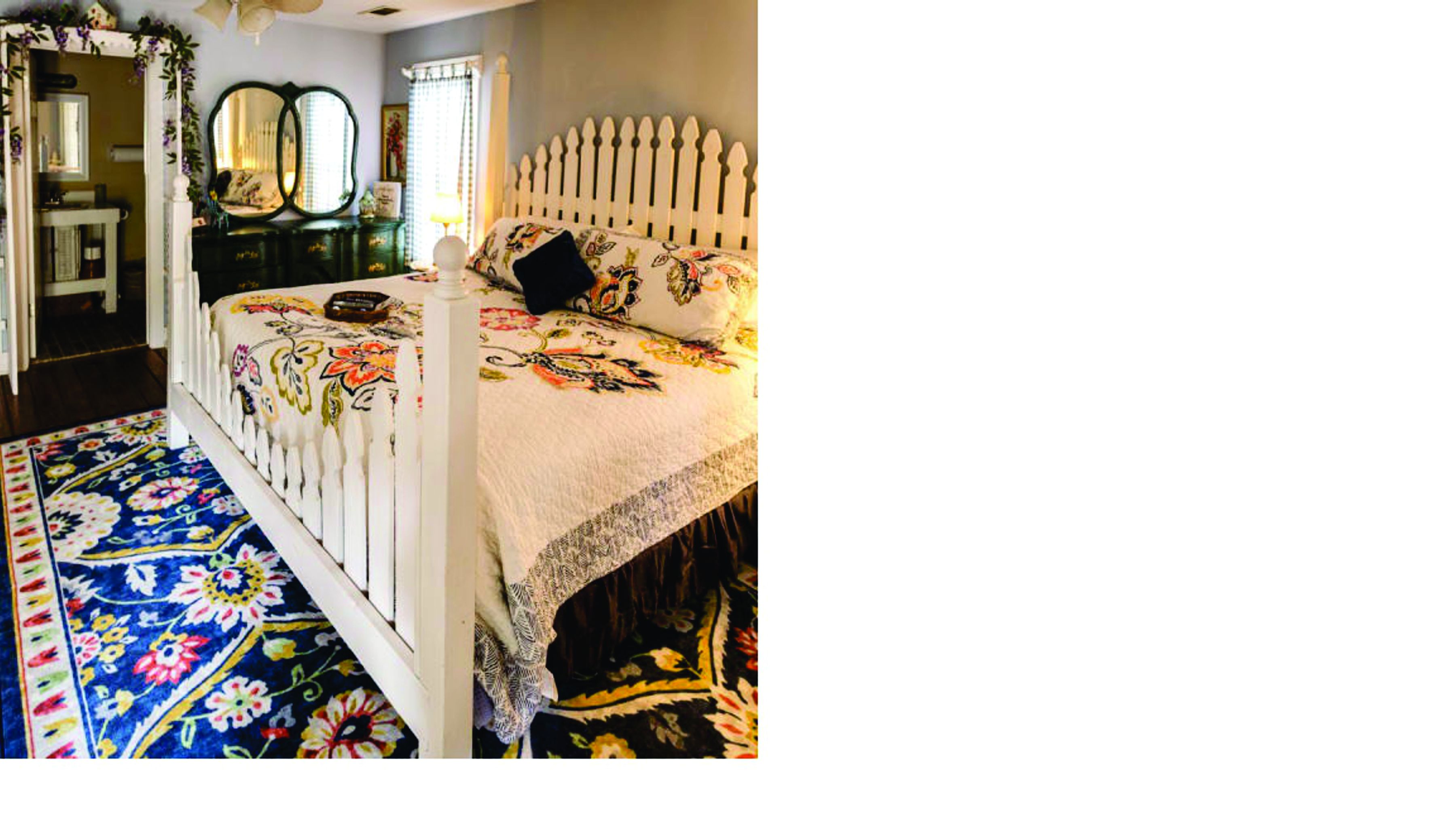 Une chambre à coucher avec un lit blanc, une couvre-lit à motifs floraux et un tapis bleu à motifs.