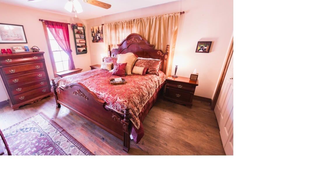 Un dormitorio con una cama de madera, un aparador, una mesita de noche y una ventana con cortinas.
