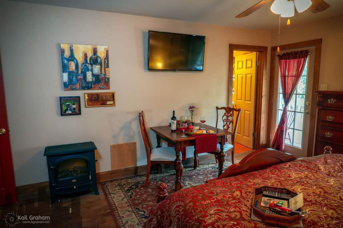 Une pièce confortable avec un lit, une table en bois et des chaises, un téléviseur et une cheminée.