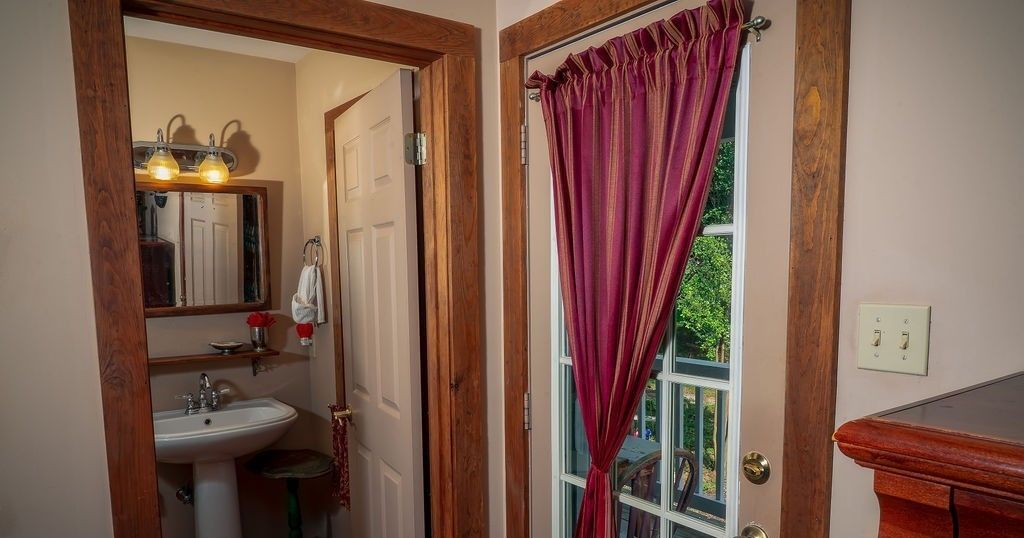 A bathroom with a sink, mirror, and wooden door.