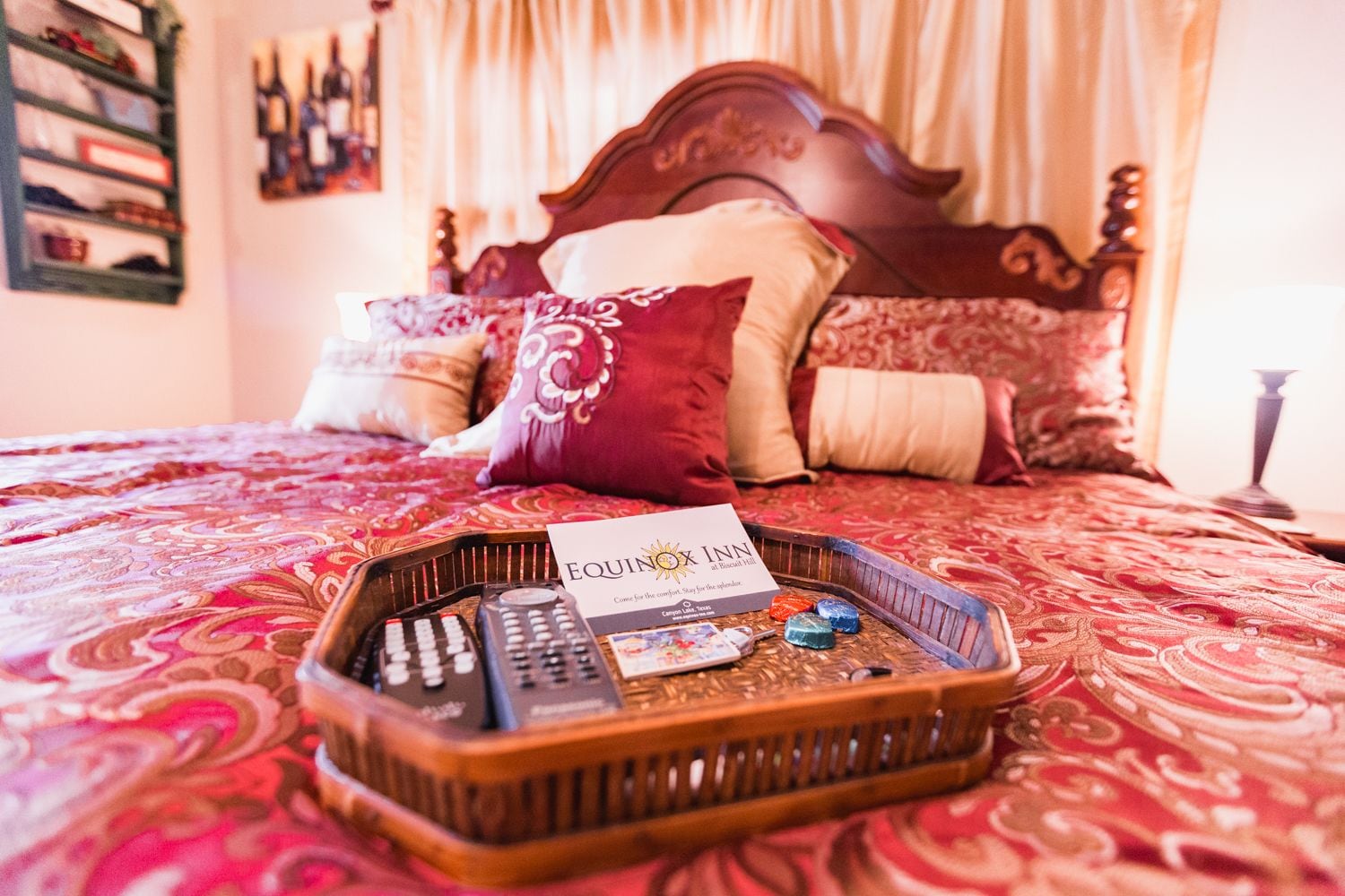 A hotel room with a bed, a tray with remote controls, a card, and decorative pillows.