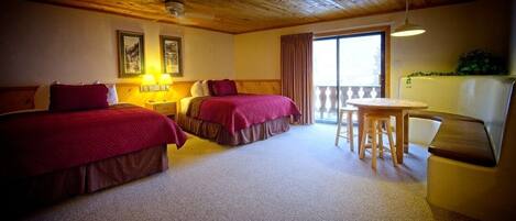 Een hotelkamer met twee bedden, een eettafel en een balkon.