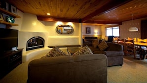 Una sala de estar acogedora con chimenea, un sofá, una mesa de comedor y un televisor.