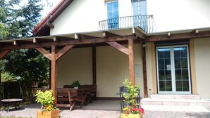 Un patio coperto con mobili in legno, piante in vaso e un'ampia finestra.
