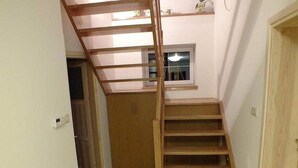 Un corridoio stretto con una scala in legno che conduce a un pianerottolo.