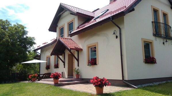 A two-story house with a sloped roof, multiple windows, and a balcony. - Agroturystyka Wielkie Leźno (Brzozie)