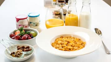 A breakfast setting with cereal, yogurt, fruit, and milk.