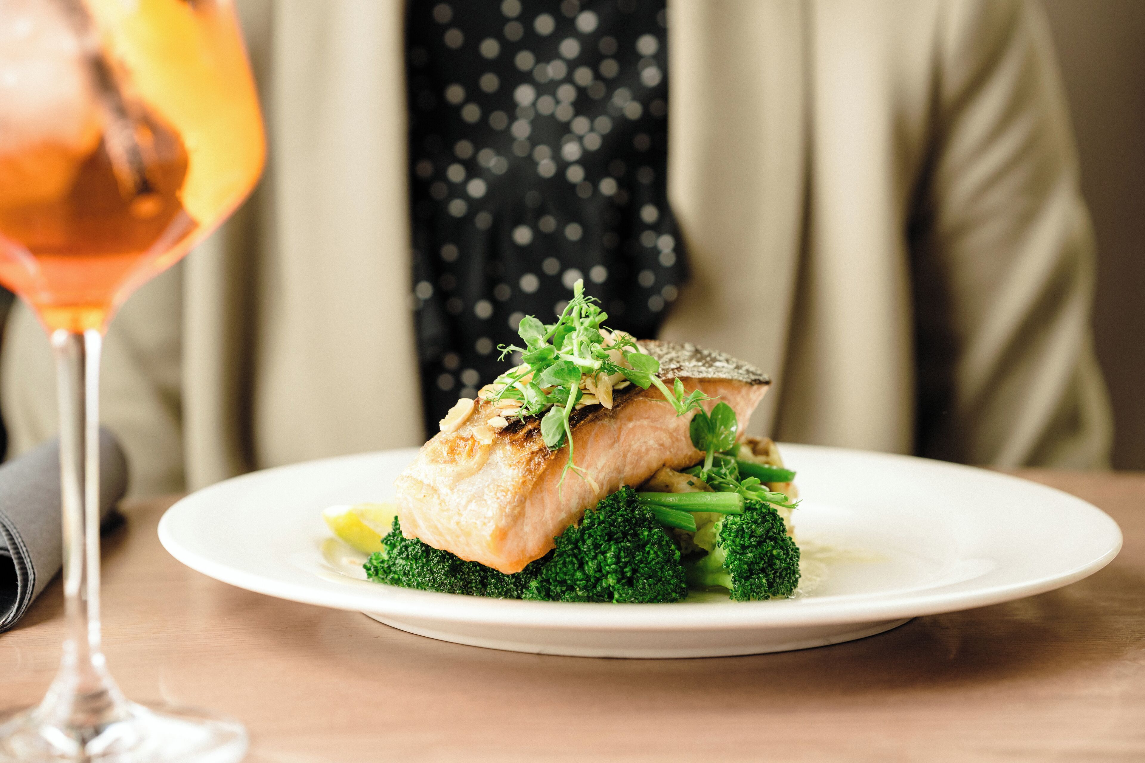 A plate of food with a piece of fish and broccoli on a white plate.