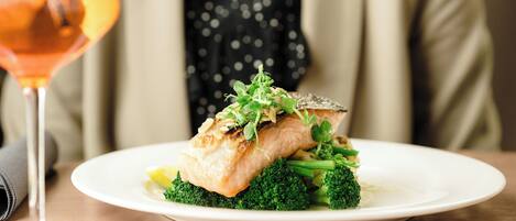 A plate of food with a piece of fish and broccoli on a white plate.