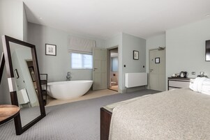 A modern bedroom with a large bed, a built-in bathtub, and a walk-in closet.