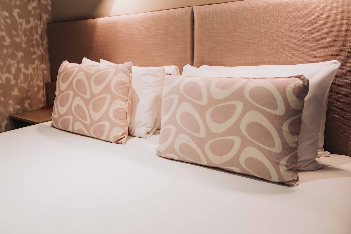 Una cama con cabecera y dos almohadas estampadas.