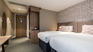 Une chambre d’hôtel avec deux lits, un bureau, une armoire et une porte de salle de bain.