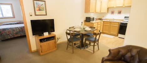 A compact living space with a dining area, kitchenette, and a bedroom.
