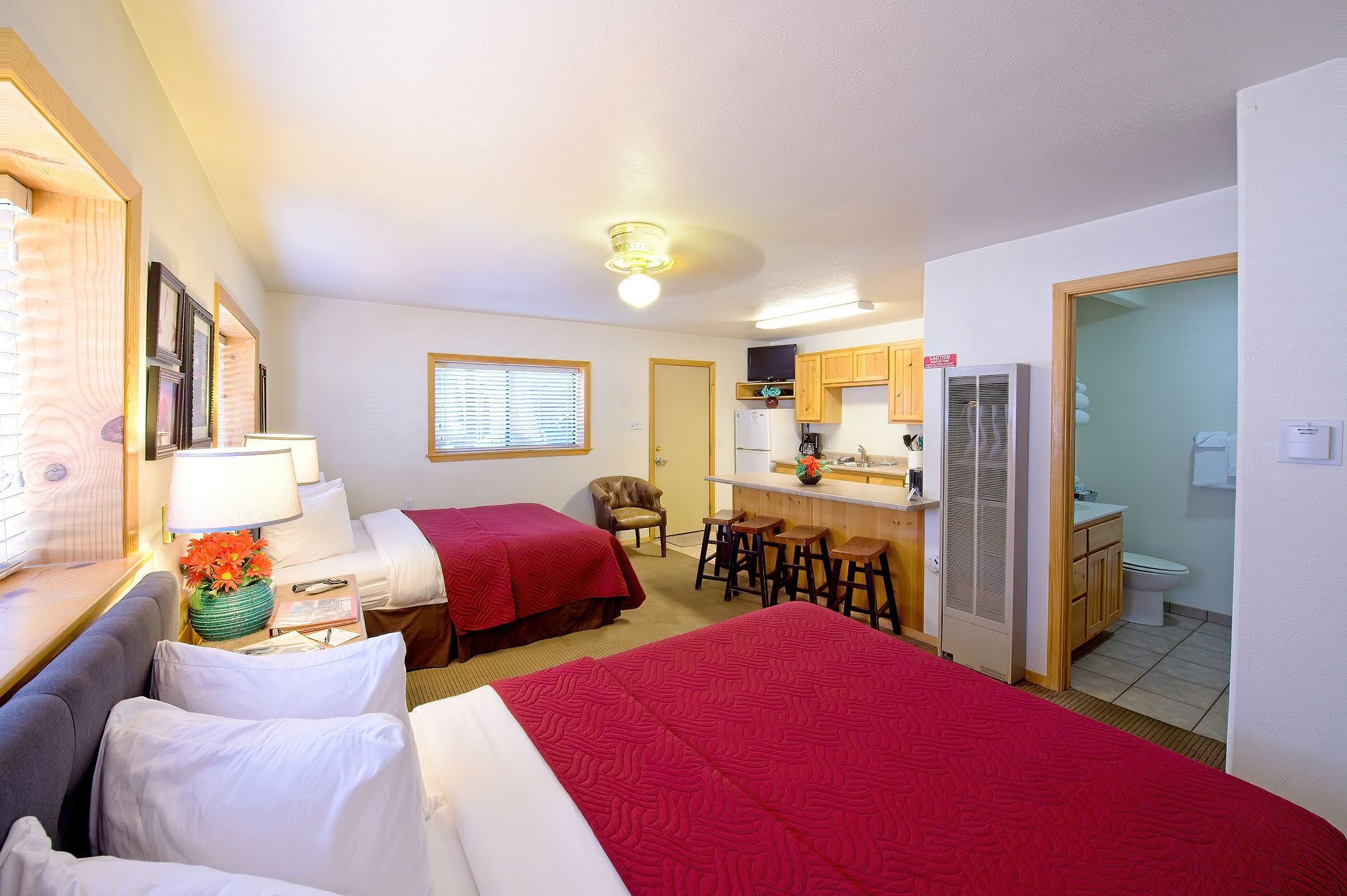 Ett hotellrum med två sängar, ett litet kök, ett badrum och en matplats.