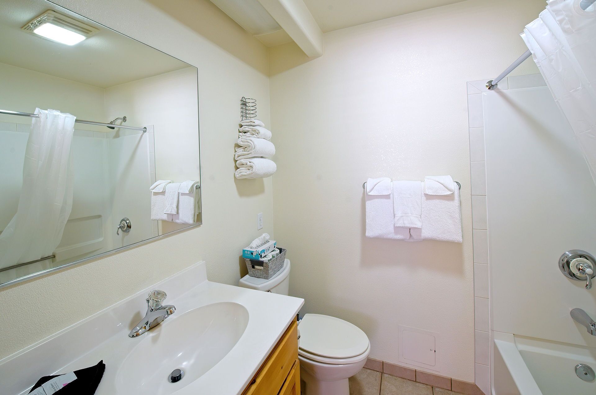 A bathroom with a sink, toilet, and shower. There are towels hanging on the wall and a mirror above the sink.