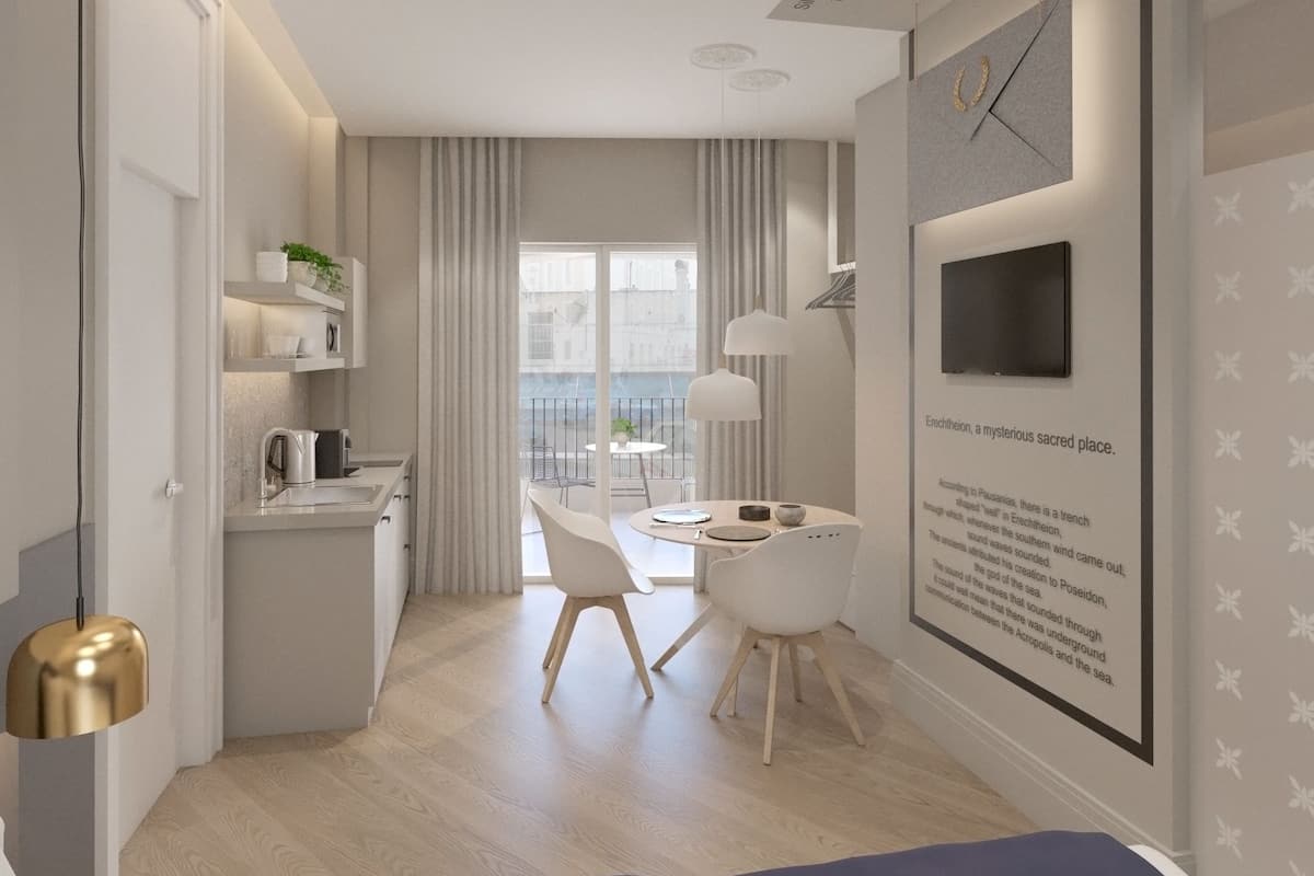 A modern kitchen with white cabinets, a kettle, and a dining area with a table and chairs.