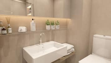 Ein modernes Badezimmer mit einem weißen Waschbecken, einer Toilette und einem Ablagefach mit Toilettenartikeln.