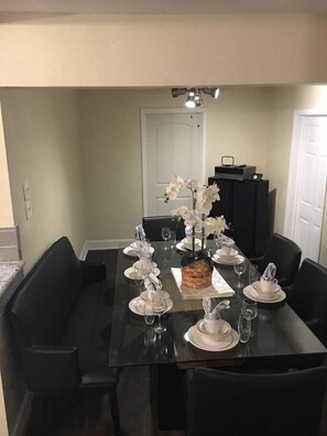 A dining table set for six with white plates, glasses, and a centerpiece of white flowers. - Alleyne's Place (Hitchcock)