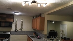 A compact kitchen with a microwave, stove, and wooden cabinets. - Alleyne's Place (Hitchcock)