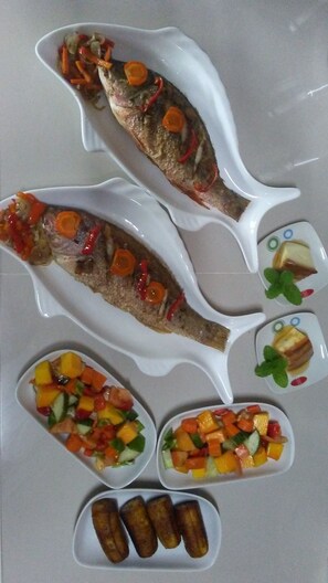 A meal with two whole fish, a fruit salad, and roasted vegetables. - El Jardín de Daynelis (Viñales)