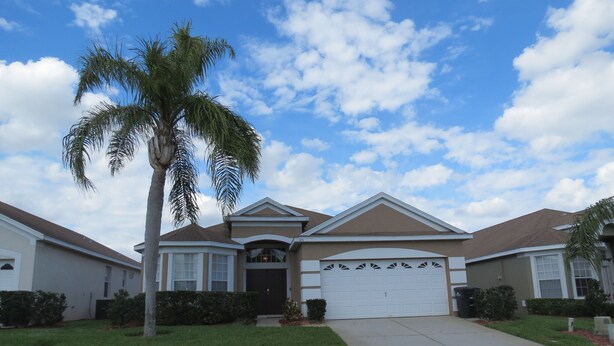 A residential house with a garage, a driveway, and a well-maintained lawn.