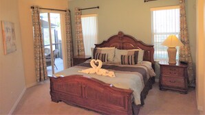 A bedroom with a wooden bed, a ceiling fan, and a nightstand with a lamp.