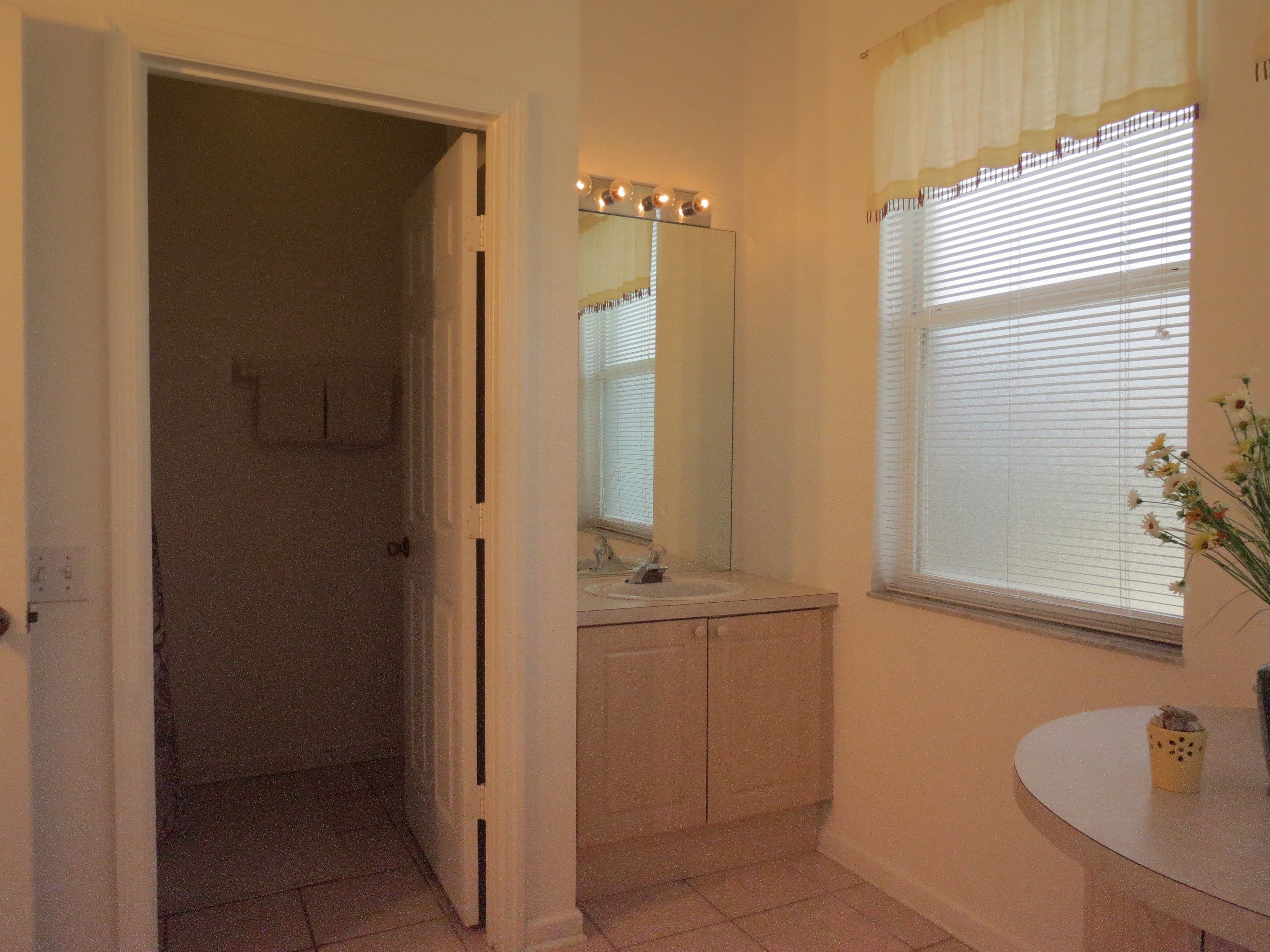A bathroom with a sink, mirror, and window with blinds.