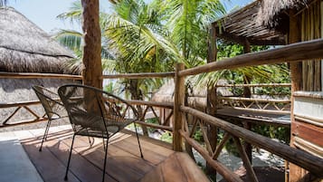 A wooden deck with a chair, surrounded by a wooden fence and palm trees.