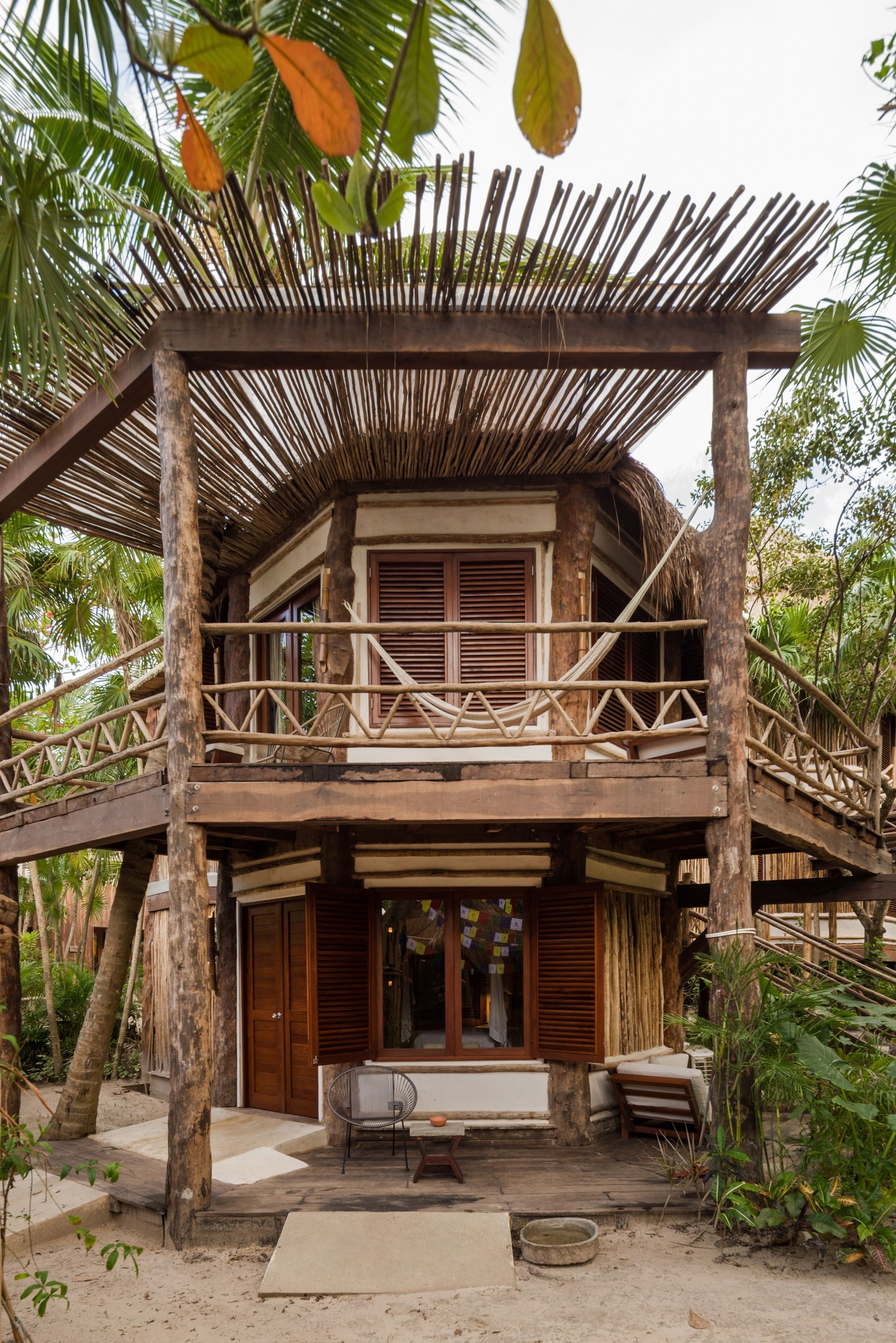 A wooden house with a thatched roof and a wooden balcony.