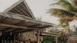 A poolside area with a thatched-roof structure, seating, and a clear pool. - Delek Tulum (Tulum)