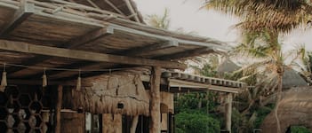 A poolside area with a thatched-roof structure, seating, and a clear pool.