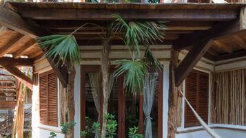 A wooden structure with a thatched roof, a balcony, and a wooden railing.