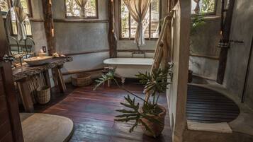 A rustic bathroom with a wooden sink, bathtub, and potted plants.